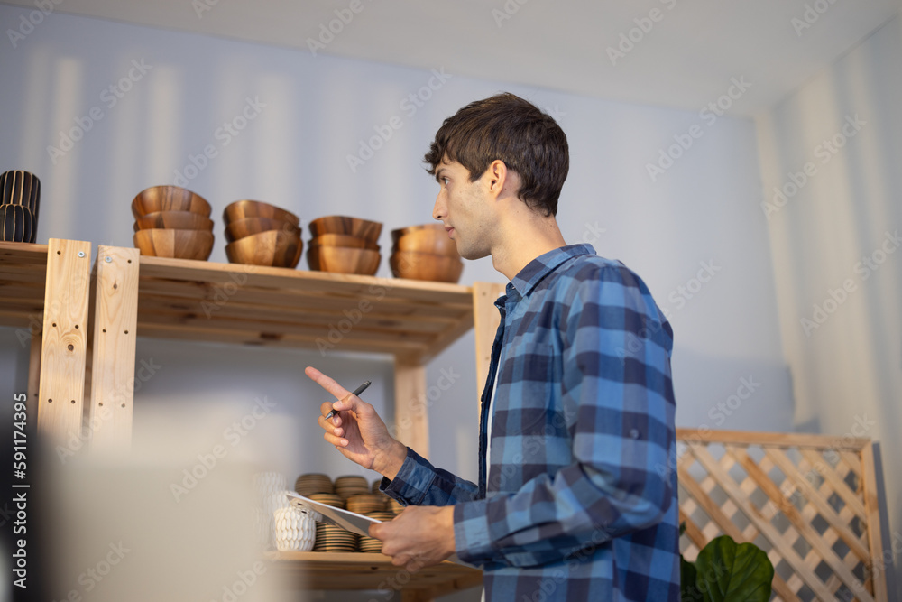 An owner of vase brand checks online and physical inventory and maintains a diary record to determine product availability. A small entrepreneur manages e-commerce with trust and commitment. An owner of vase brand checks online and physical inventory and maintains a diary record to determine product availability. A small entrepreneur manages e-commerce with trust and commitment.