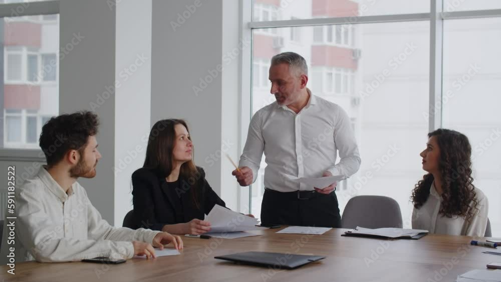 Smiling business people applauding while sitting at a table in a conference room. Company employees applaud their boss after a motivational speech. Smiling business people applauding while sitting at a table in a conference room. Company employees applaud their boss after a motivational speech.
