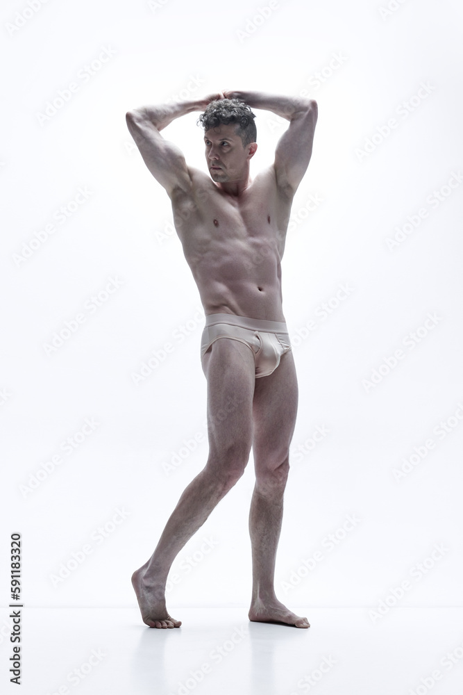 Full-length portrait of handsome man with muscular, relief, attractive body posing shirtless against white studio background. Concept of male body aesthetics, men's beauty, inspiration Full-length portrait of handsome man with muscular, relief, attractive body posing shirtless against white studio background. Concept of male body aesthetics, men's beauty, inspiration