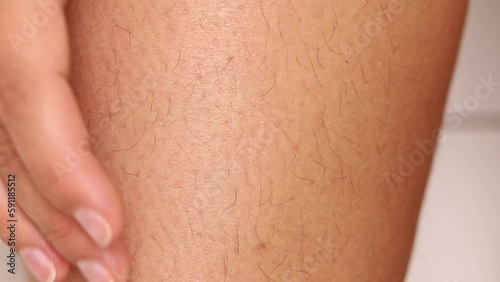 Female hand stroking hairy legs against hair growth closeup. Body skin covered with hair, unshaven legs. Skincare, epilation, beauty treatment. Self acceptance and body positive concept.