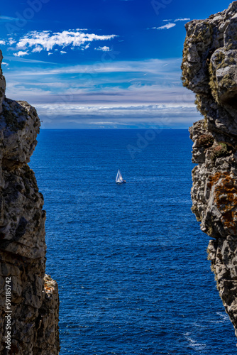 Cliffs And Sail Boat At Pointe De Penhir At The Finistere Atlantic Coast in Brittany, France
