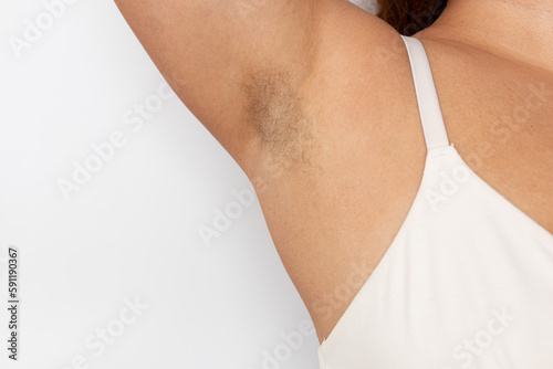 Woman with hairy underarms closeup, free copy space, white background. Raised arm with armpit hair. Female beauty trend, freedom, sensitive skin, feminism, body positive, naturalness. Hygiene concept. photo