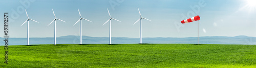 Windräder auf einer Grünen Wiese in einer hügeligen Landschaft