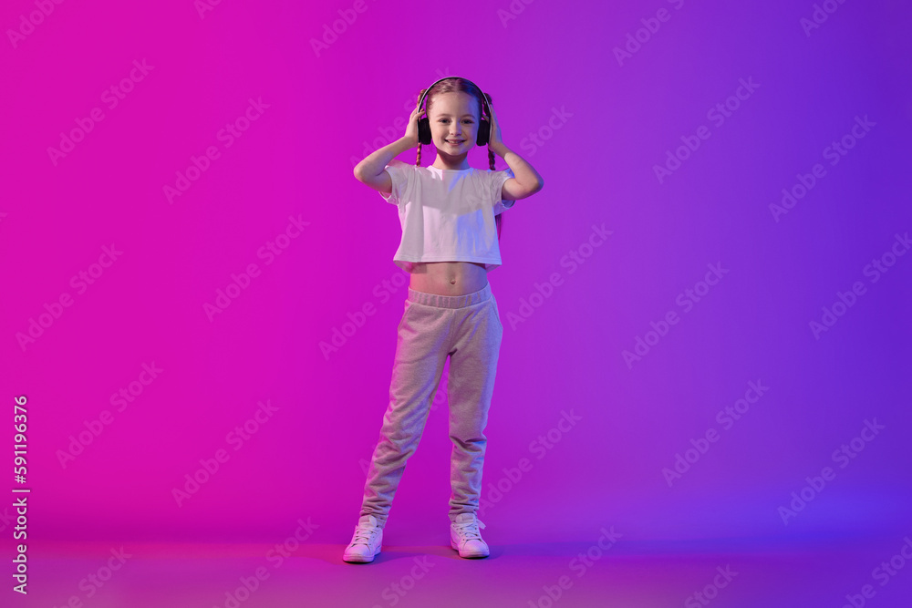 Sweet preteen child girl in summer outfit using wireless headphones Sweet preteen child girl in summer outfit using wireless headphones