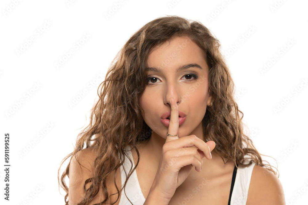 young curly womanholding index finger at her lips, saying 'shh' on a white background young curly womanholding index finger at her lips, saying 'shh' on a white background
