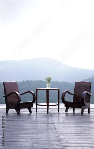 Wooden chair and table on terrace with view of sky and mountain behind 