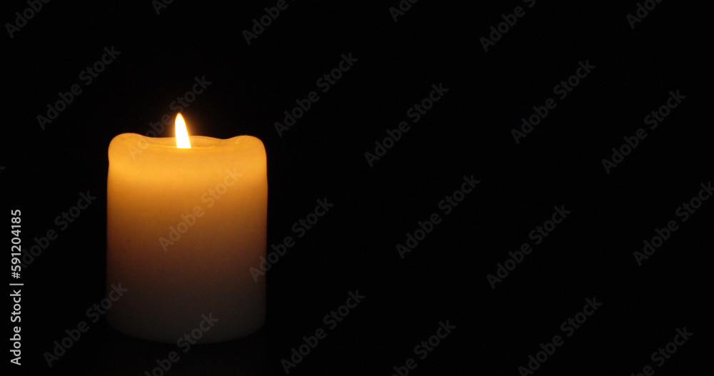 A burning insulated candle on a dark background. A burning insulated candle on a dark background.