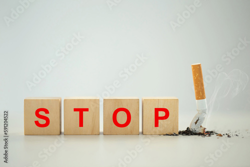 World No Tobacco Day Concept. Stop Smoking. A wooden block with the word stop written in red with Tobacco cigarette butt on the floor.Quit bad habits, health care concept. No smoking.