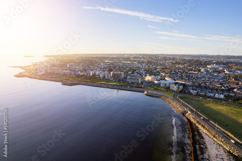 Aerial view on Salthill area of Galway city, Ireland. Warm sunny day. Popular educational center and tourist hub with vivid night life. Sun flare.