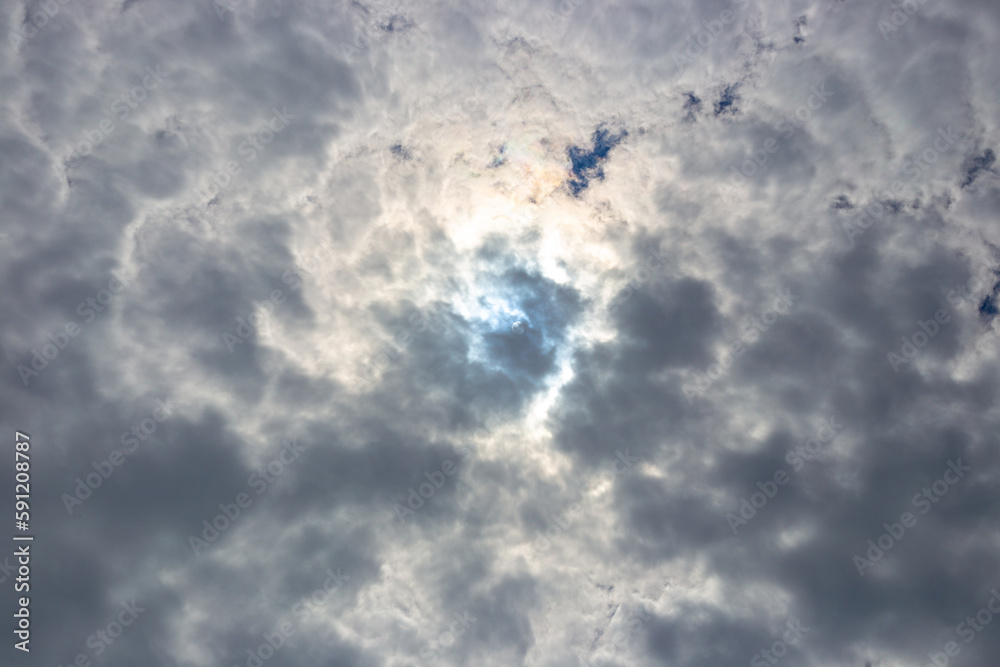 Dark contrasting sky with clouds and the contour of the sun behind the clouds Dark contrasting sky with clouds and the contour of the sun behind the clouds