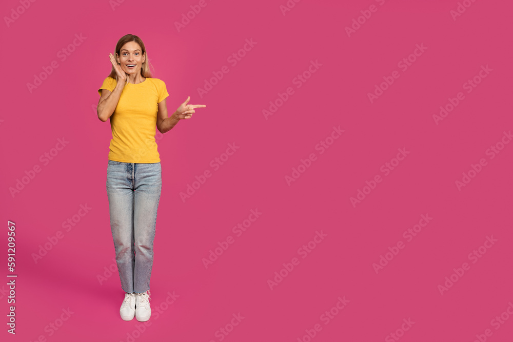 Shocked cheerful middle aged european blonde female pointing finger at free space