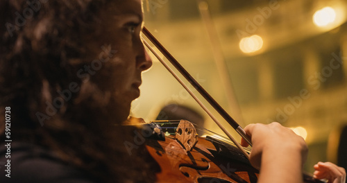 Cinematic Close Up Shot of Professional Symphony Orchestra Violin Player Playing on Classic Theatre with Curtain Stage during Music Concert. Performers Playing Music for Audience