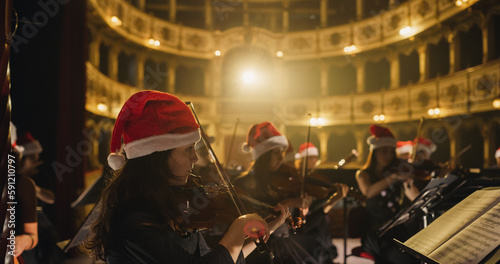 Cinematic Shot of Symphony Orchestra Musicians Wearing Santa Hats and Performing on the Stage of a Classic Theatre During a Classical Music Concert. Focused Performers Playing Different Instruments