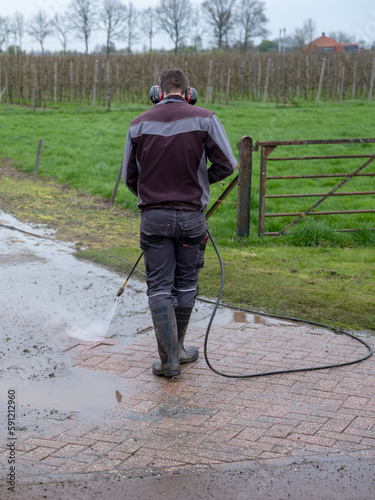 man cleans driveway with pressure washer