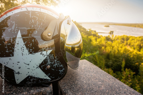 Motorcycle helmet with a mirrored visor on the background of nature photo