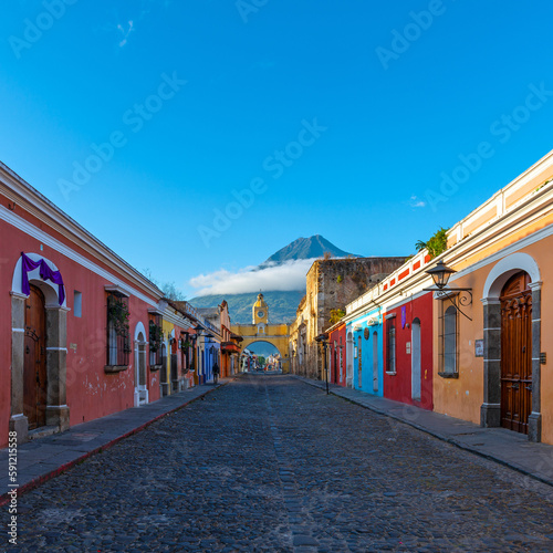 Main street of Antigua city at sunrise with Agua volcano and Santa Catalina arch, Guatemala.