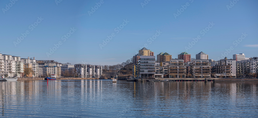 Waterfront apartment house and boats at a pier in the bay Hammarby sjö, a sunny spring day in Stockholm