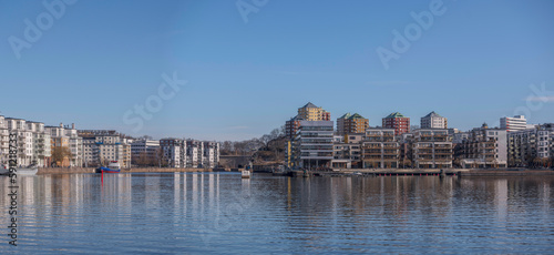Waterfront apartment house and boats at a pier in the bay Hammarby sjö, a sunny spring day in Stockholm