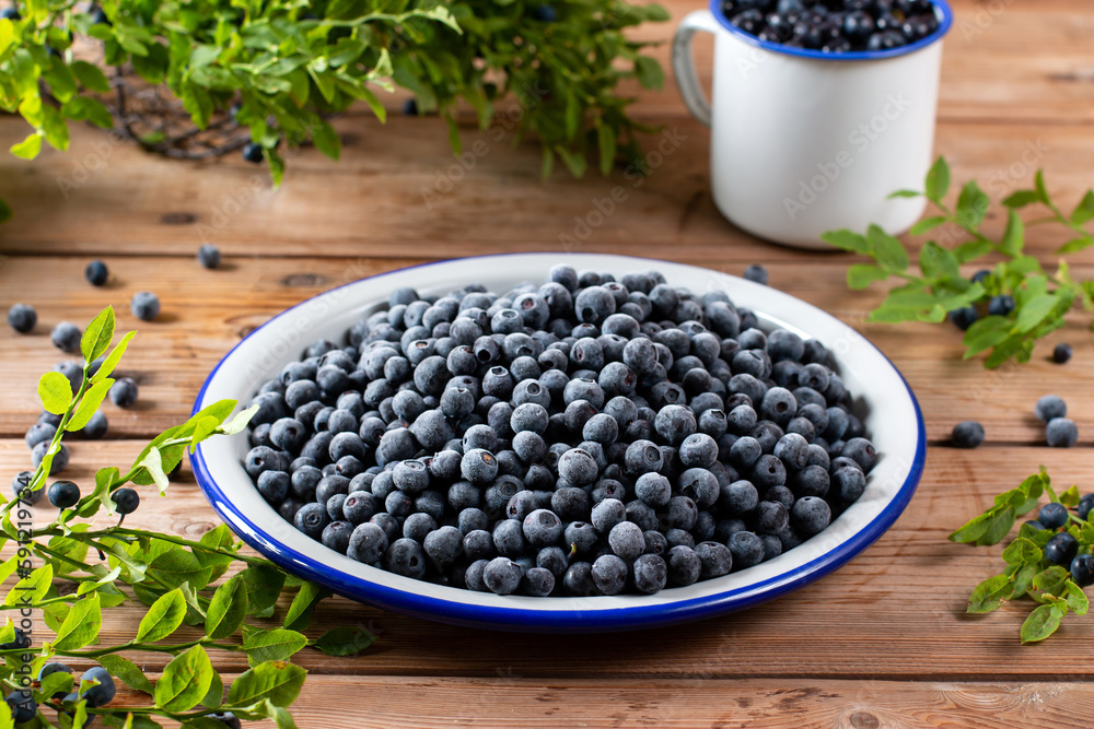 Frozen blueberries in a metal bowl on wooden table Frozen blueberries in a metal bowl on wooden table