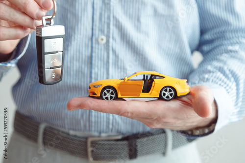 Businessman Holding a Car Key and Toy Car, Vehicle Dealer or Rent concept
