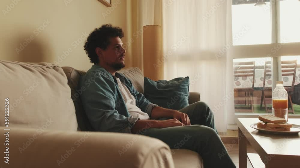 Young man eating lunch while sitting in the living room watching TV Young man eating lunch while sitting in the living room watching TV