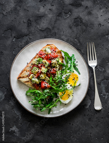 Healthy breakfast, snack - avocado, tomatoes bruschetta, boiled egg and arugula on a dark background, top view