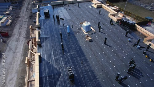 New apartment building under construction on sunny day. Residential low rise house construction project. Aerial inspection of plywood roof and walls sheathing frame with industry plank.