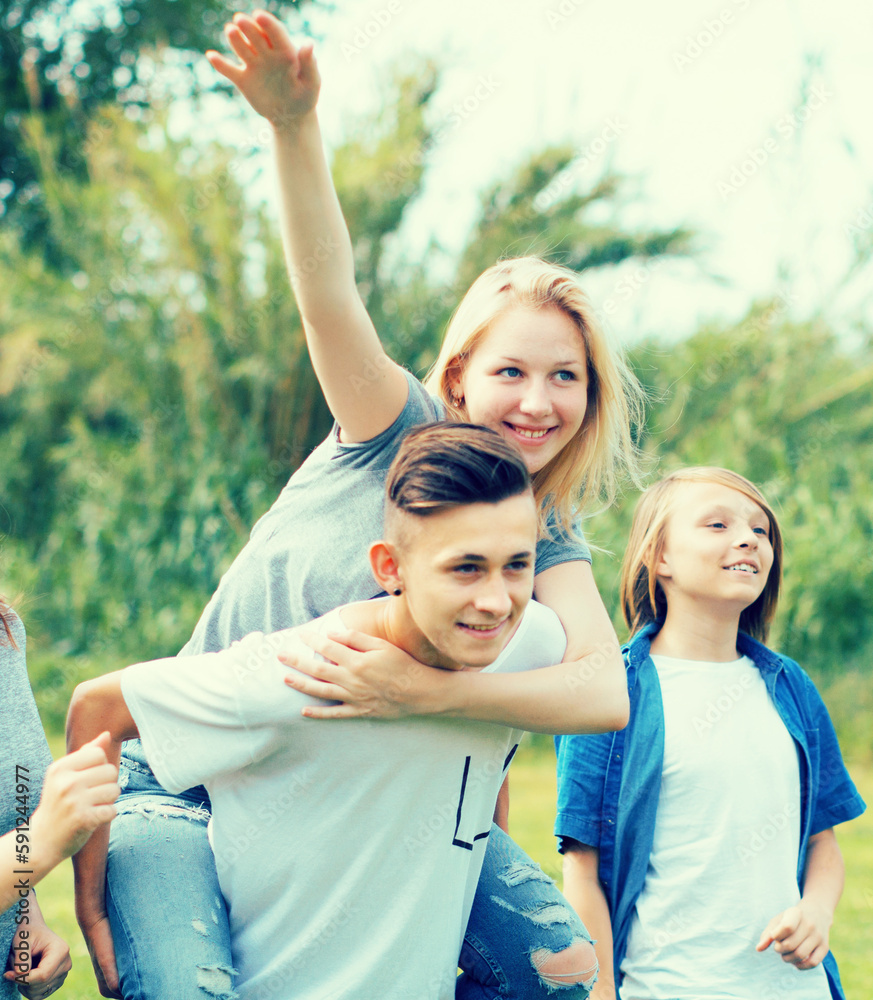 teenagers running through green lawn in summer in park