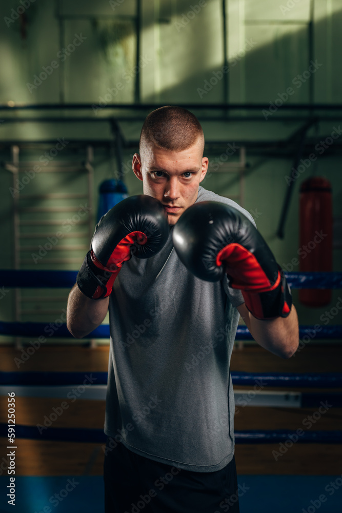A Caucasian boxer stands in a guard position and looks at the camera
