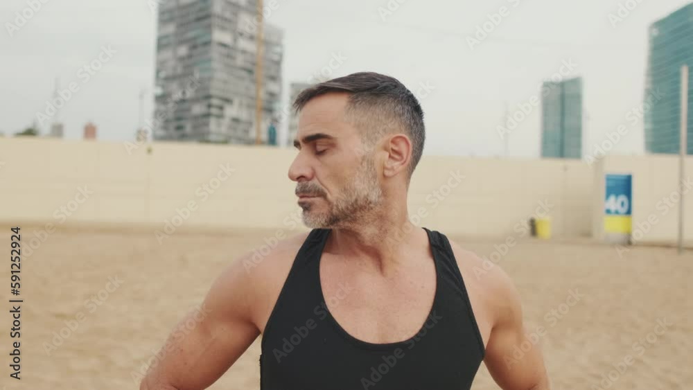 Man works out in the beach and stretches the neck muscles Man works out in the beach and stretches the neck muscles