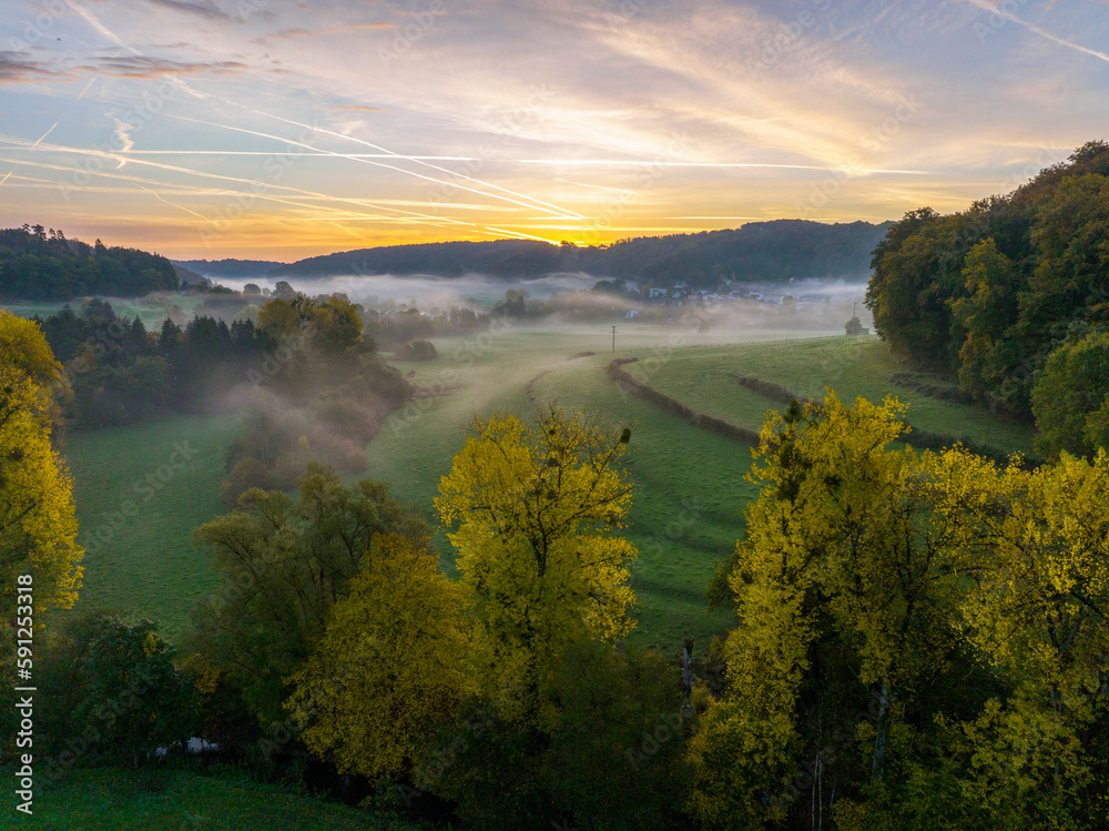 Aerial drone Sunrise view Above autumn colored forest and Valleys in Luxembourg, covered in morning fog