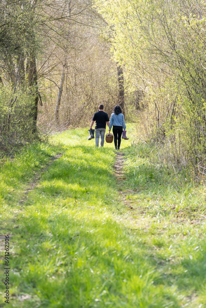Fototapeta premium couple cheminant dans la forêt avec un panier de provision et des bottes