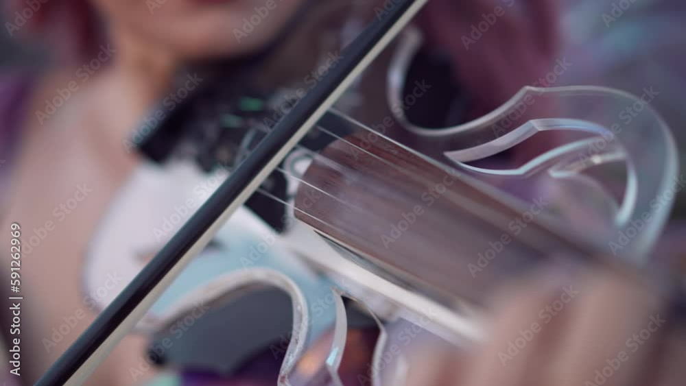 Close-up violin bow playing on strings of musical instrument in slow motion. Closeup unrecognizable Caucasian woman enjoying music outdoors