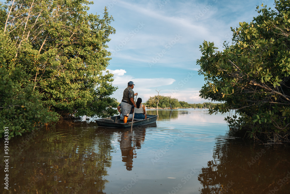 Paisaje de un manglar con un pequeño grupo de personas en una barca.