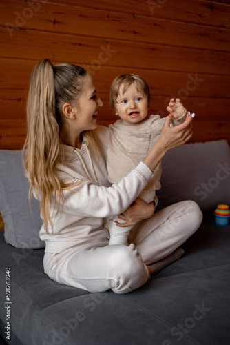 A woman sits on a couch with her baby