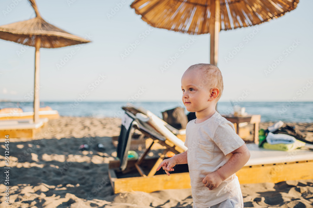 Little boy standing on the beach and looking into the distance with joy.