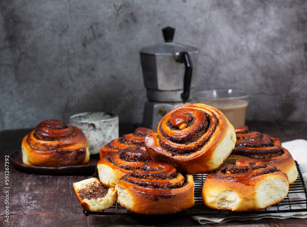 Yeast dough cinnabons with poppy seeds, raisins and candied fruits, served with coffee. Rustic style.