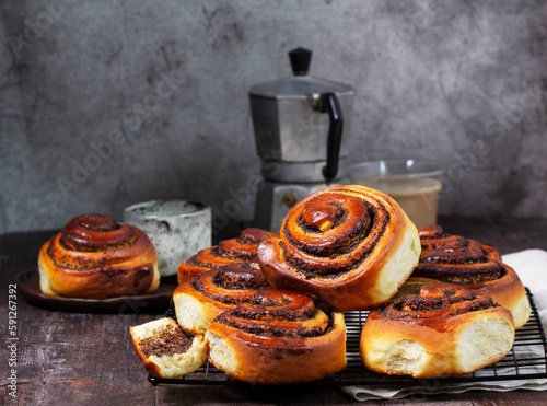 Yeast dough cinnabons with poppy seeds, raisins and candied fruits, served with coffee. Rustic style.