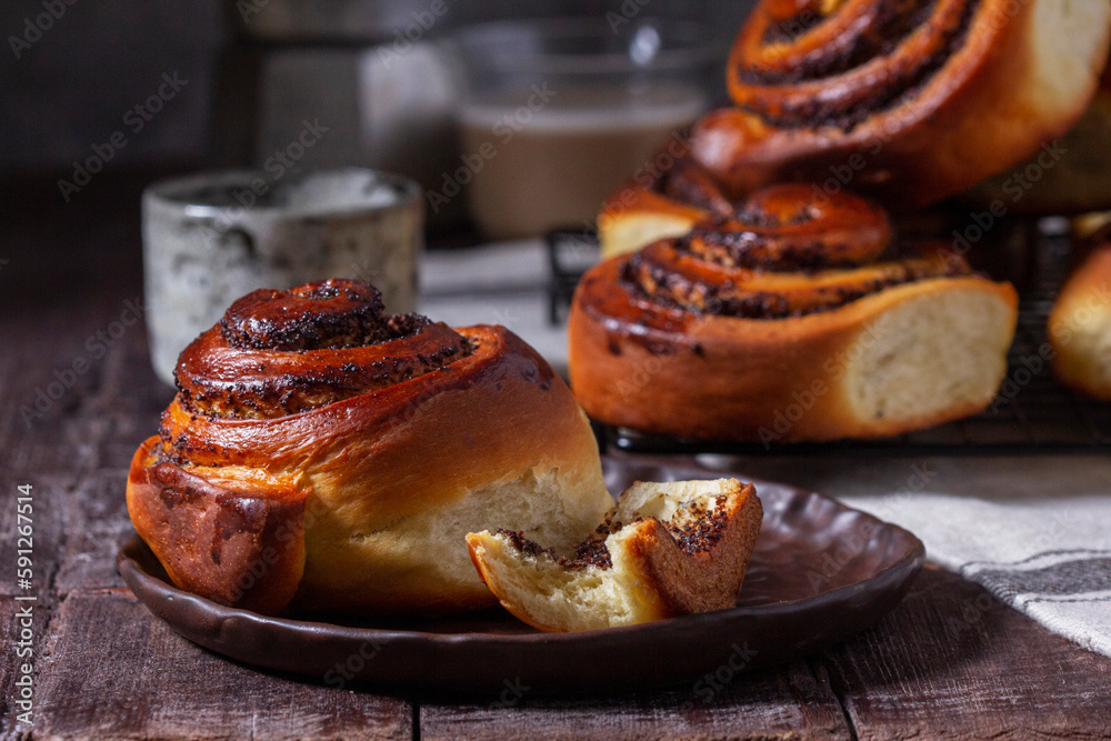Yeast dough cinnabons with poppy seeds, raisins and candied fruits, served with coffee. Rustic style.