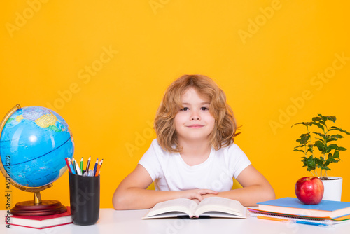 School kid reading book. School and education concept. Portrait of cute child school boy, isolated on yellow background. Back to school.