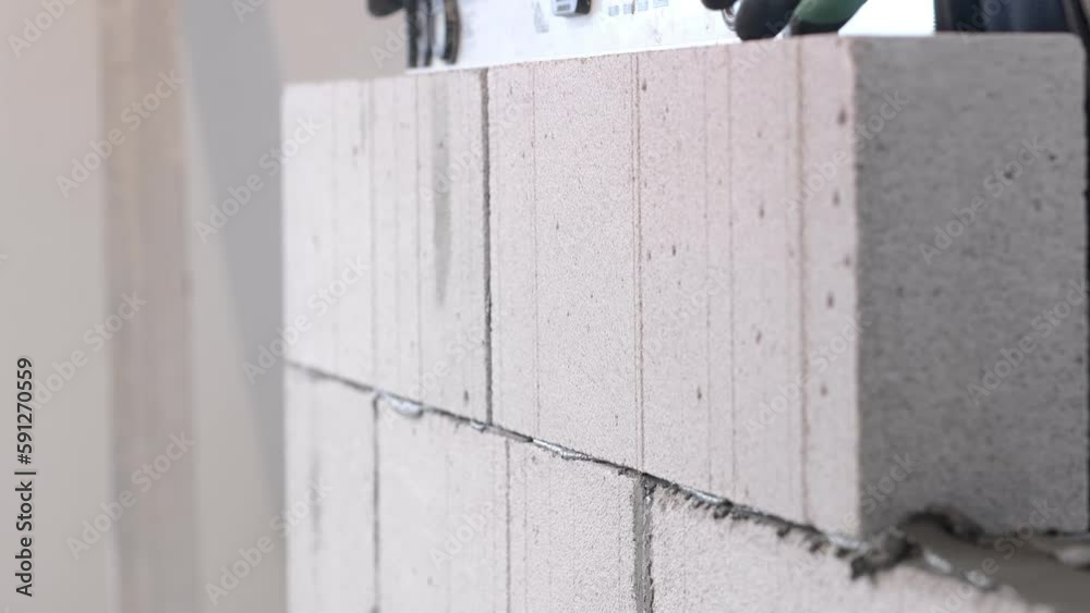 The builder places the block during the construction of the wall. The builder places the block during the construction of the wall.