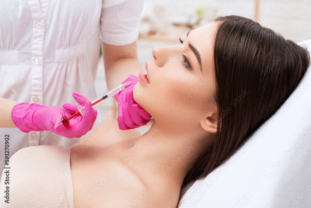 Cosmetologist does injections for lips augmentation of a beautiful woman. Women's cosmetology in the beauty salon. Cosmetologist does injections for lips augmentation of a beautiful woman. Women's cosmetology in the beauty salon.