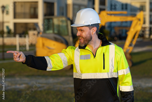 Worker at construction site. Builder in hardhat. Construction man with helmet. Worker at construction with helmet. Industry worker at construction building. Builder at site building with excavator.