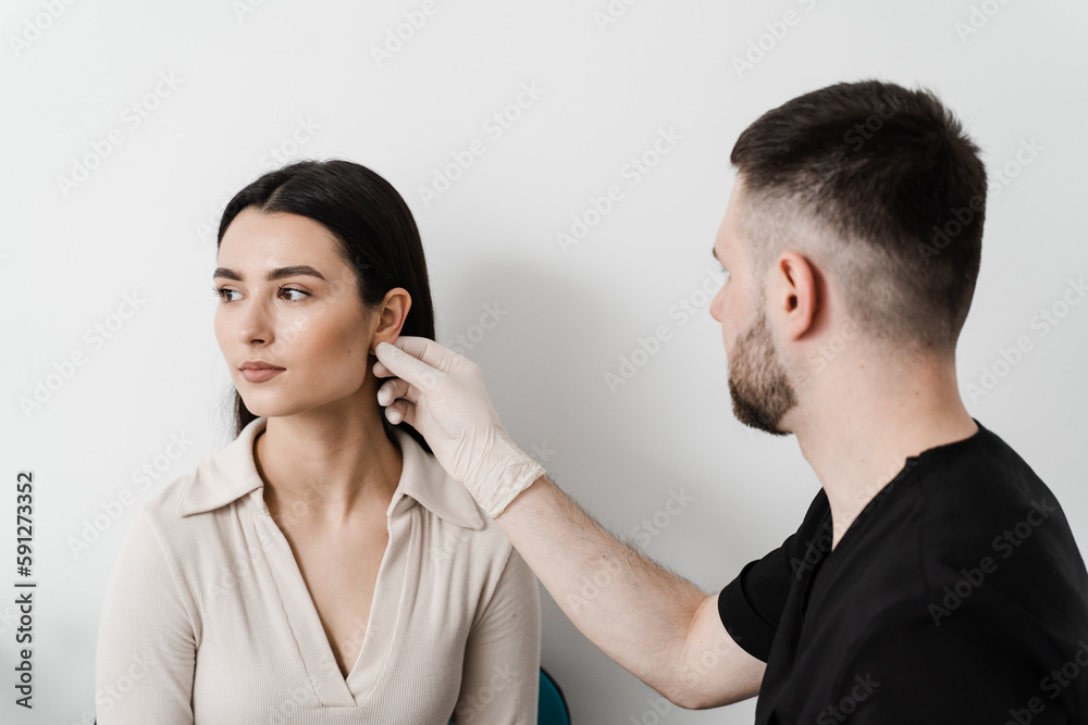 Otoplasty is surgical reshaping of the pinna, or outer ear for correcting an irregularity and improving appearance. Surgeon doctor examines girl ear before otoplasty cosmetic surgery. Otoplasty is surgical reshaping of the pinna, or outer ear for correcting an irregularity and improving appearance. Surgeon doctor examines girl ear before otoplasty cosmetic surgery.