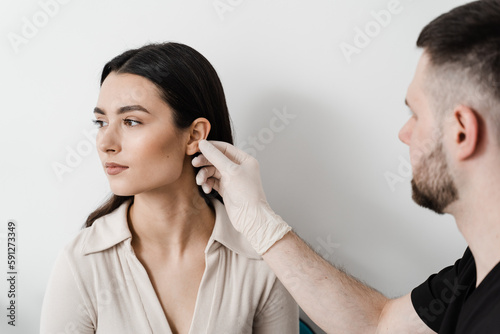 Otoplasty is surgical reshaping of the pinna, or outer ear for correcting an irregularity and improving appearance. Surgeon doctor examines girl ear before otoplasty cosmetic surgery.
