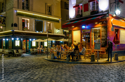 Typical night view of cozy street with tables of cafe and easels of street painters in quarter Montmartre in Paris, France © Ekaterina Belova