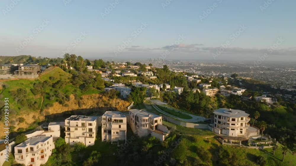 Backwards reveal of residential houses lit by bright sun at golden hour. Living in Hollywood hills. Los Angeles, California, USA Backwards reveal of residential houses lit by bright sun at golden hour. Living in Hollywood hills. Los Angeles, California, USA