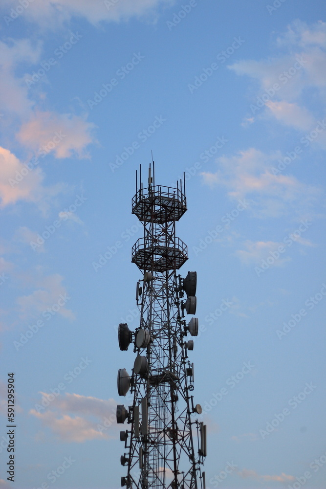 High Telecommunication booth tower in blue sky with scattered white clouds
