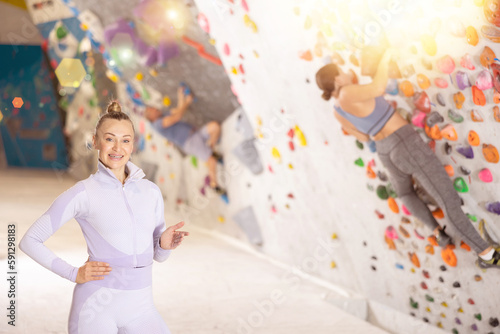 Adult athletic woman in sportswear posing on climbing wall..
