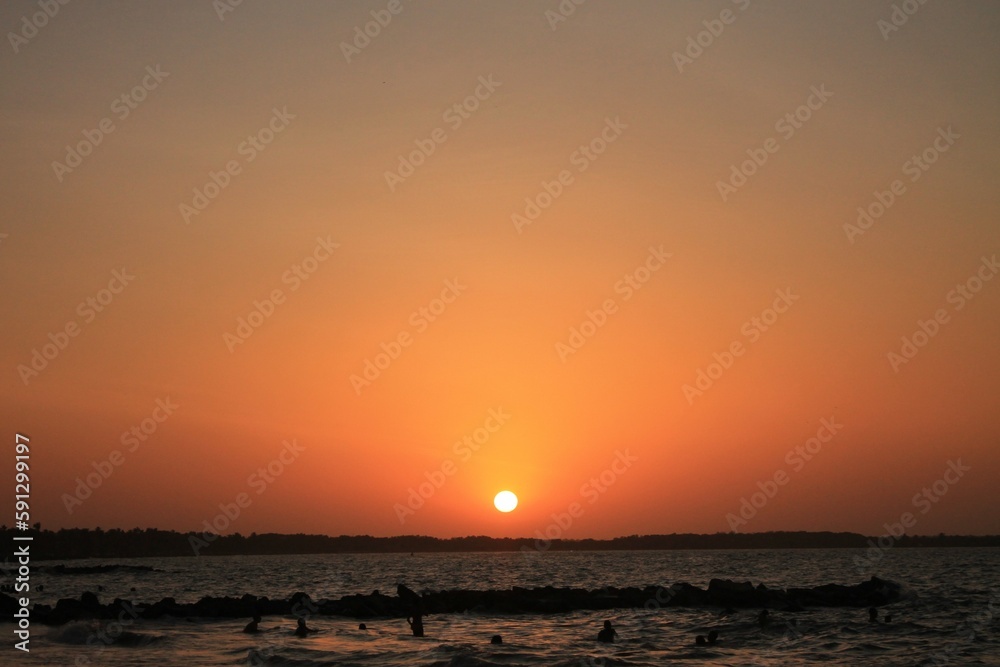 La cálida puesta de sol tiñe el cielo y el mar, creando una vista impresionante en la playa.